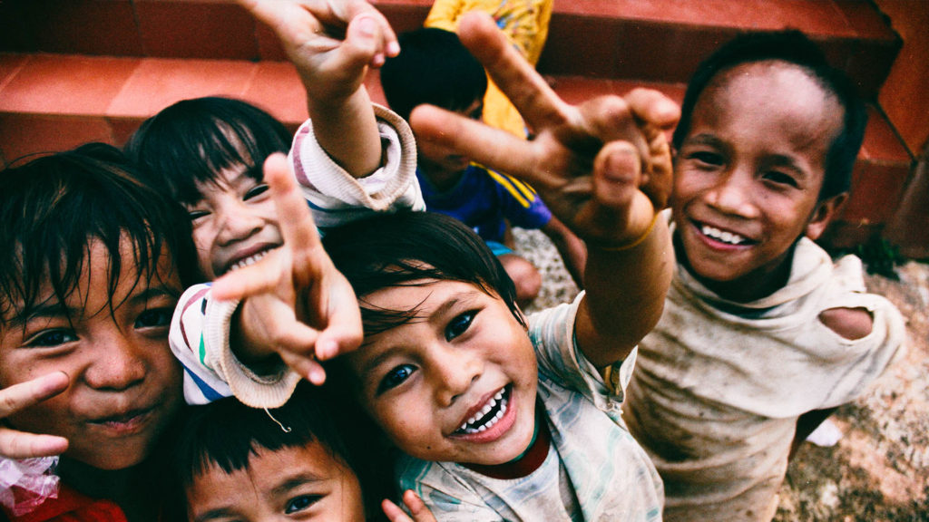 Eine Gruppe von Kindern hält einem Finger mit Peace Zeichen entgegen